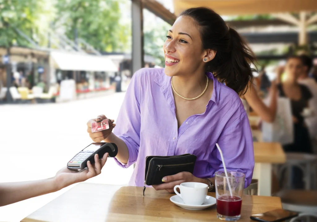 Woman uses her credit card in a cafe to build credit and practice good credit habits.