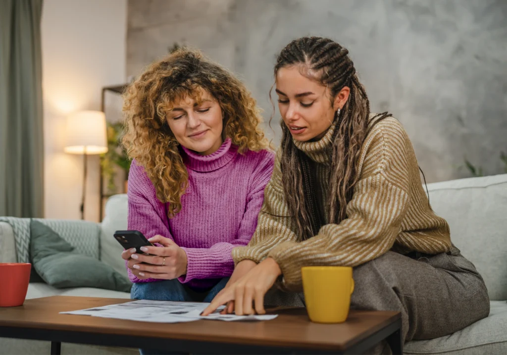 A person offers emotional support to a loved one facing financial problems as they sit together on a couch looking at financial documents.