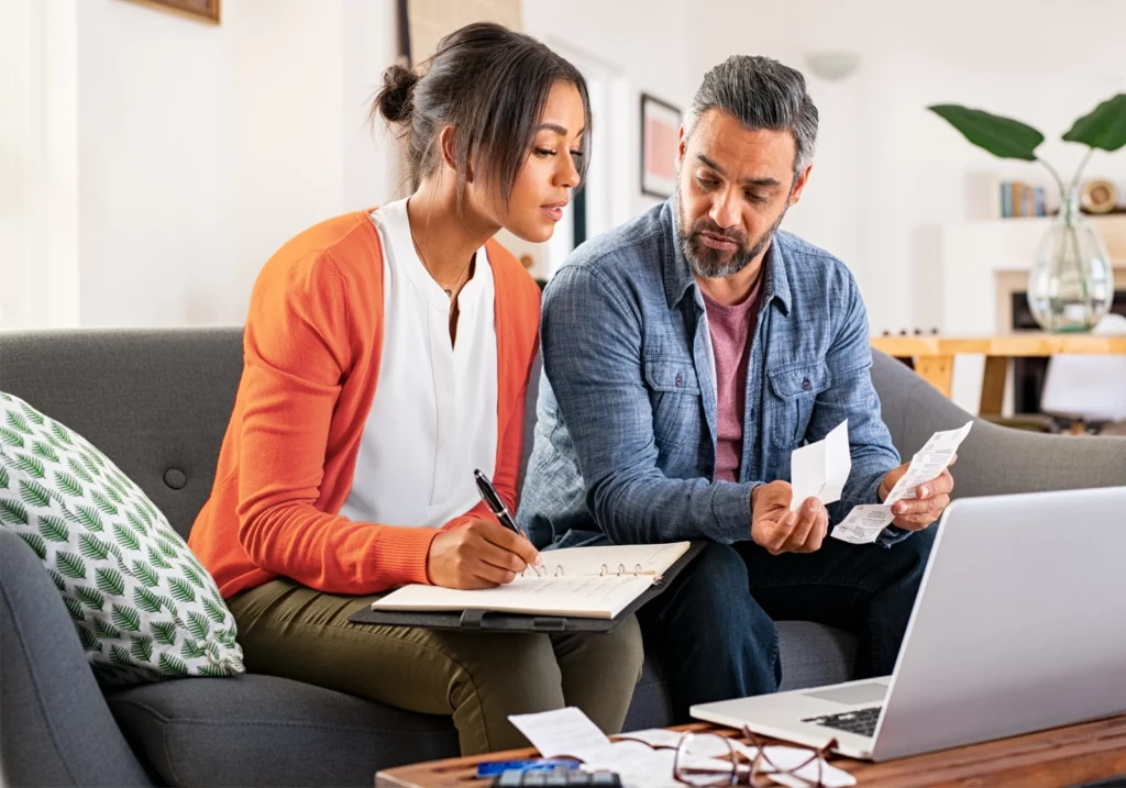 A couple sitting on a couch, reviewing their monthly spending plan