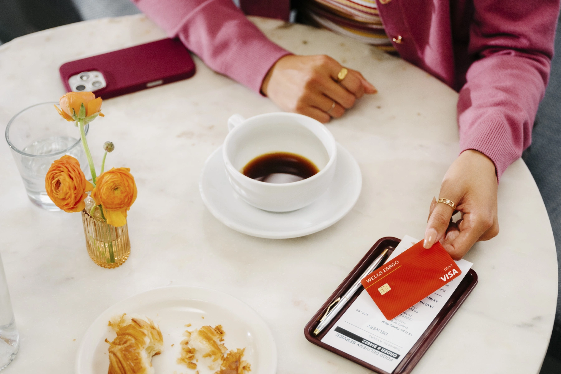 A person places their debit card on the table to pay their bill in a café.