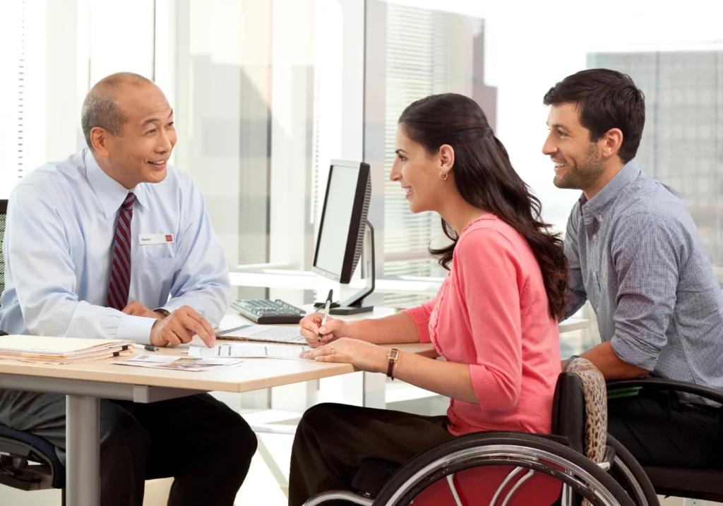 Man and woman sit in a financial institution talking with an employee.