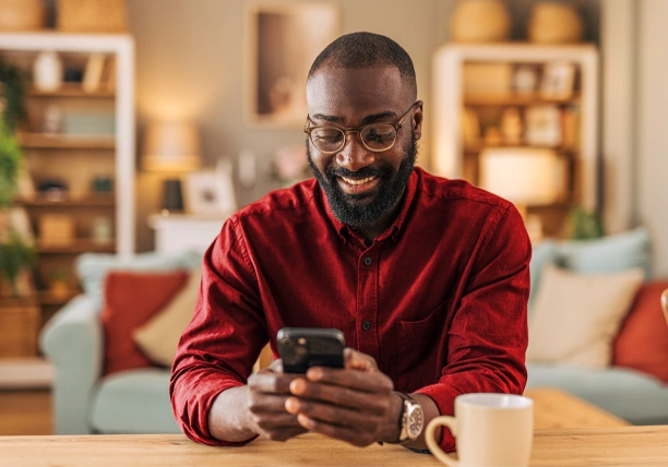 A man sits in his home and uses his smartphone to review credit details.