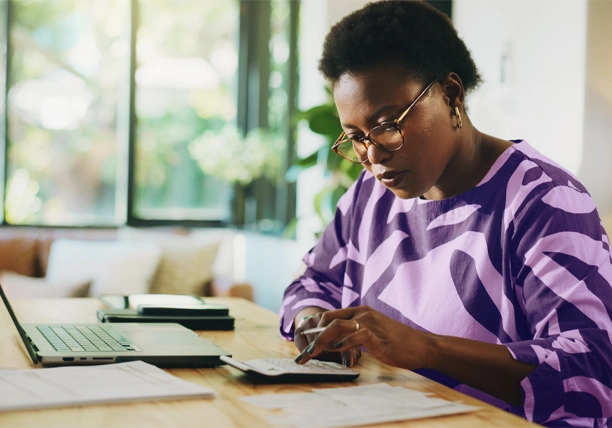 A woman uses a calculator to determine how much she needs for an emergency fund.