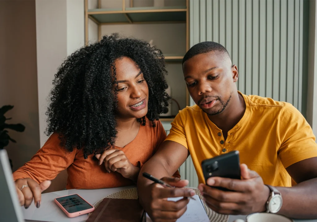 Young couple works together at a table in their home as they decide on a debt payoff method.