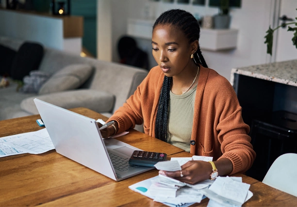 A woman reviews her monthly bills on a laptop.