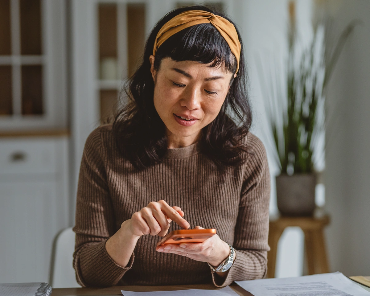 Person using a phone and reviewing papers while learning digital banking basics.