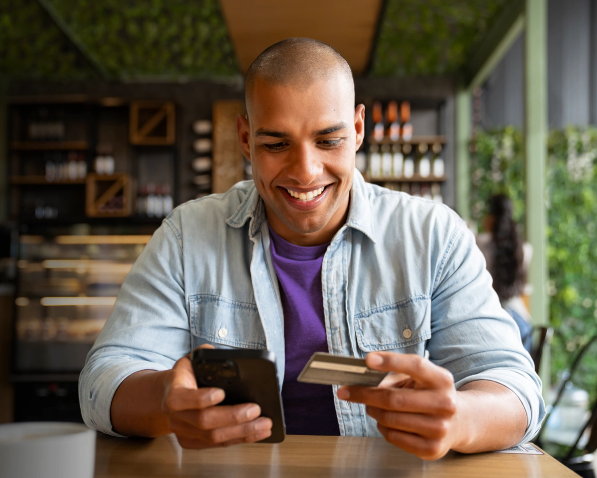 Person using a phone and payment card while learning how credit works.