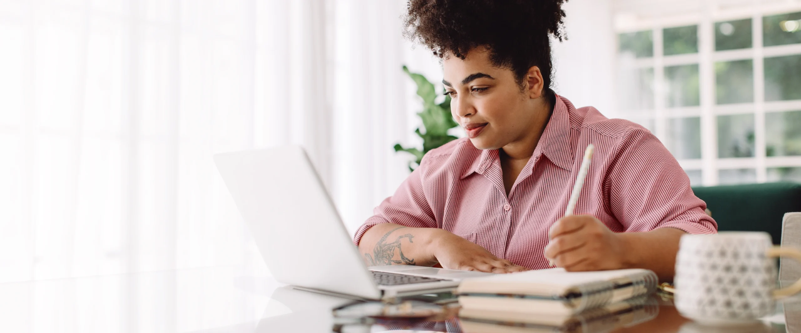 Person using a laptop and notebook to make a debt management plan.