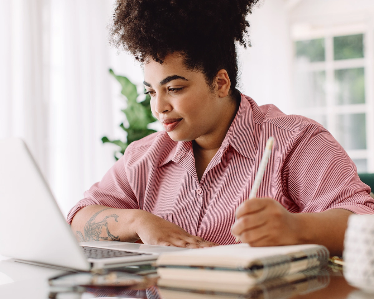 Person using a laptop and notebook to make a debt management plan.