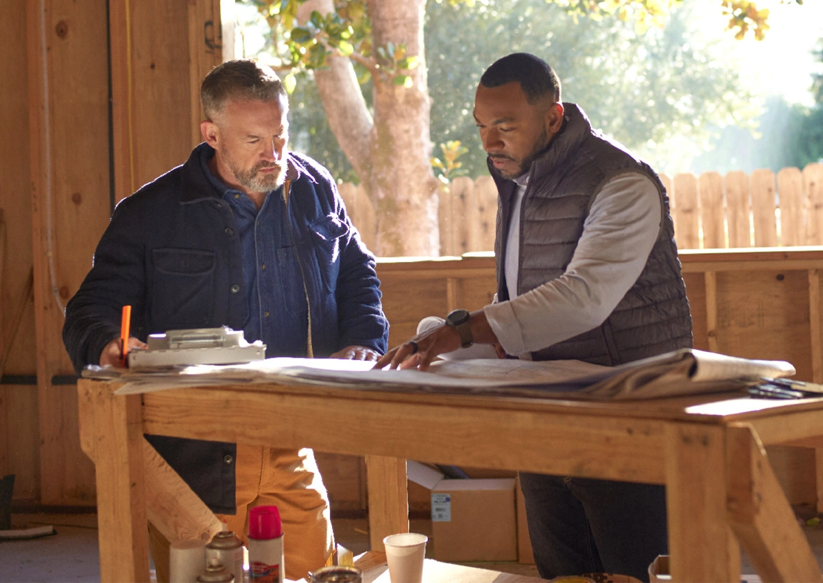 Two people review plans and documents together at a worktable.