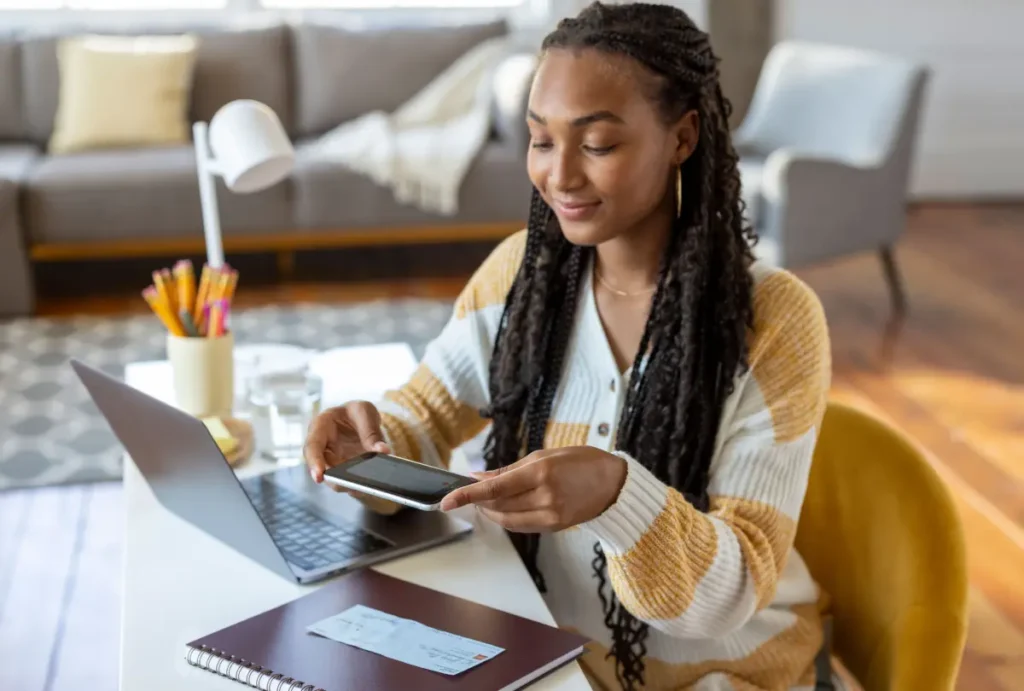 Person using a phone to scan a check, building money skills at home.