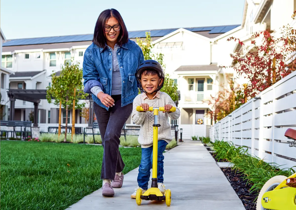 Adult helping a child move forward while enjoying time together outside.