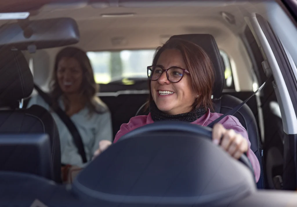 Smiling woman driving in a car while doing gig work.