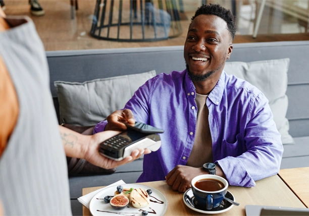 A man uses a debit card to pay for a meal in a cafe.