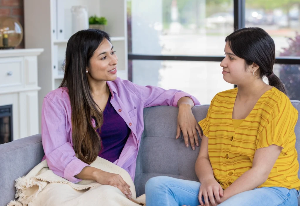Mom talks to her daughter about money management on the couch.