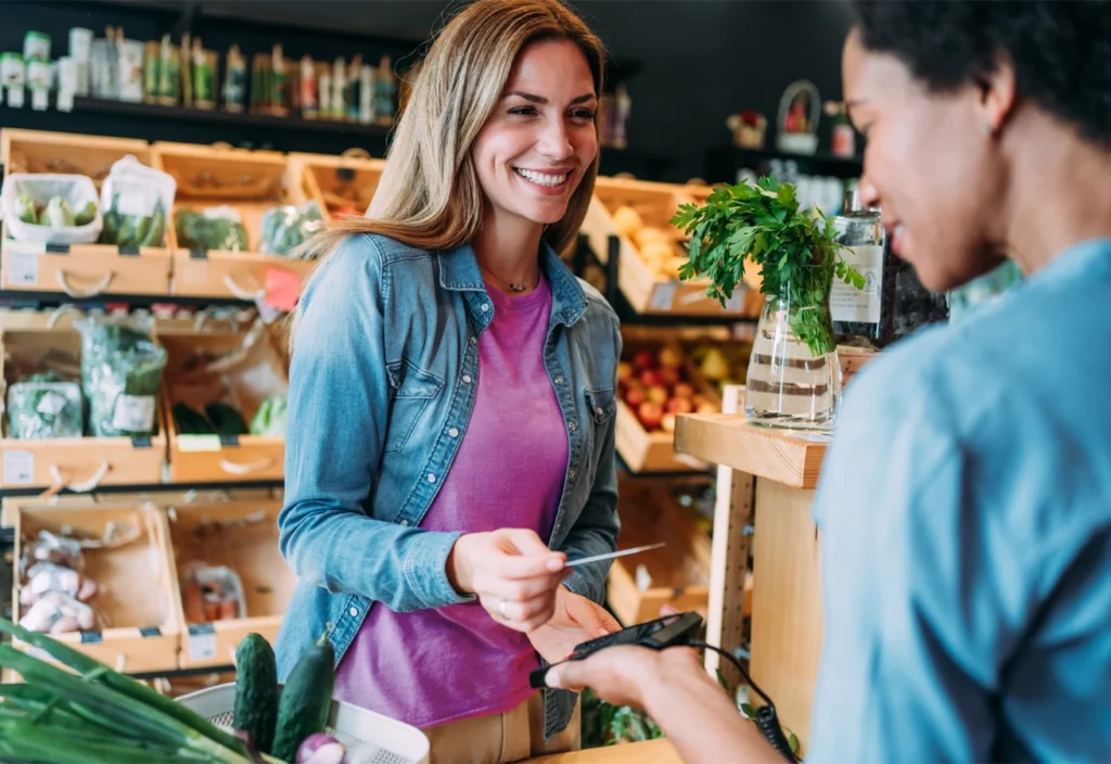 Woman hands her credit card to a cashier in a grocery store.