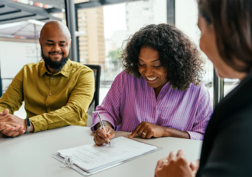 Smiling couple confidently fills out a credit application in an office setting after boosting their credit score.
