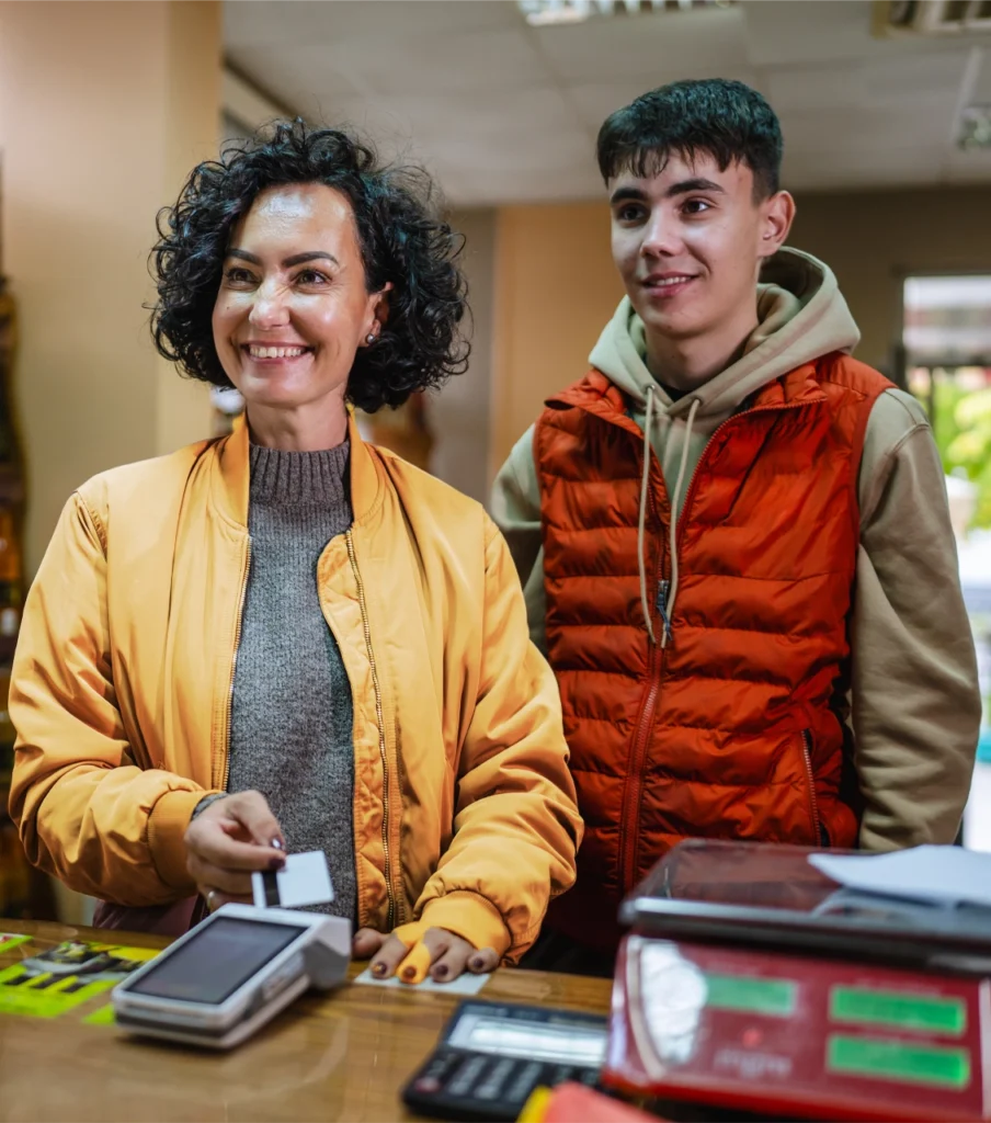 Mother and son smiling while using a card to make a purchase.