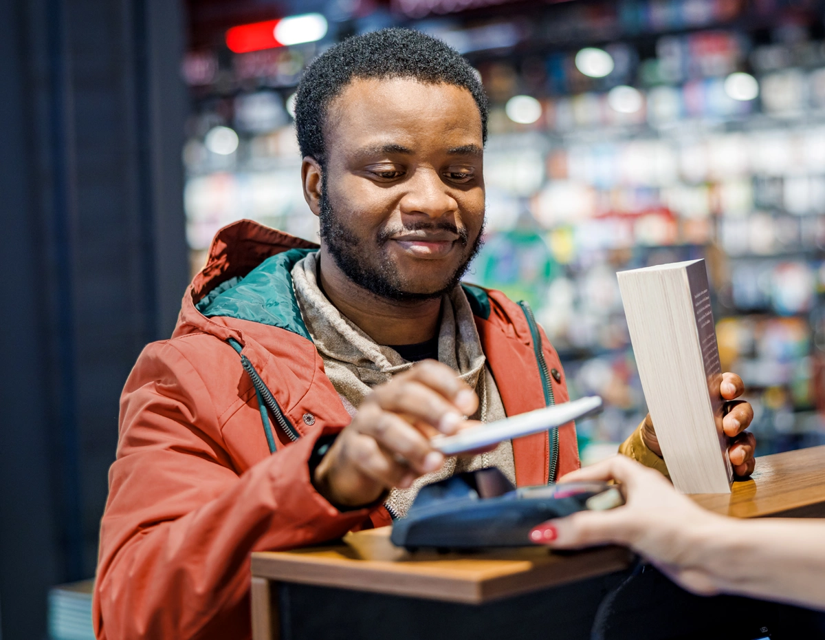Person using a phone to make everyday purchase while managing financial goals.